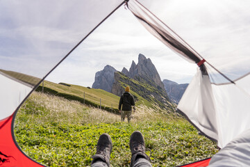 First-person view of a woman watching a man enjoy the views from a tent high up on the mountain