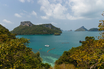 Boats float on a tranquil bay surrounded by lush hills under a clear sky