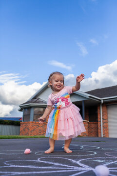 Joyful little girl in sparkly dress dancing outside home
