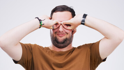 Studio, man and binoculars with hands for crazy comic, silly and goofy expression with smile. Face,...