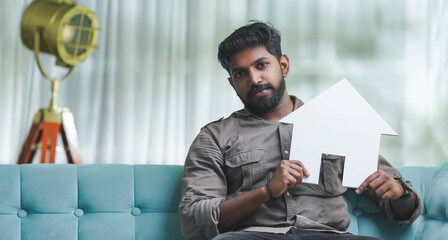 South Indian man holding house, Home insurance and loan concept image