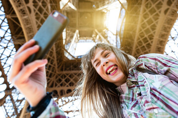 Happy girl taking a selfie under the Eiffel Tower in Paris