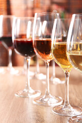 Different tasty wines in glasses on wooden table