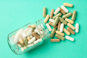 Vitamin pills and bottle on mint color background, top view