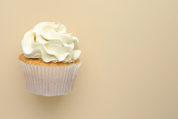 Tasty vanilla cupcake with cream on beige background, top view. Space for text