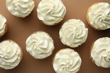 Tasty vanilla cupcakes with cream on dark beige background, top view