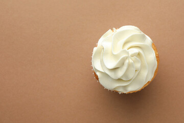 Tasty vanilla cupcake with cream on dark beige background, top view. Space for text