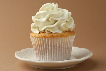 Tasty vanilla cupcake with cream on dark beige background, closeup