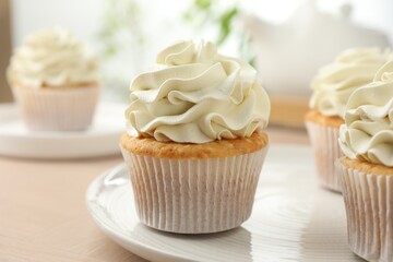 Tasty cupcakes with vanilla cream on light wooden table, closeup