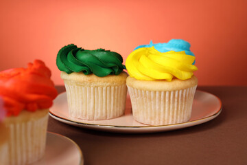 Delicious cupcakes with bright cream on color background