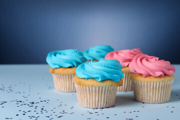 Delicious cupcakes with bright cream and confetti on blue background, space for text