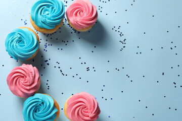 Delicious cupcakes with bright cream and confetti on light blue background, flat lay. Space for text