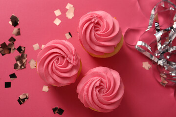 Delicious cupcakes with bright cream and confetti on pink background, flat lay