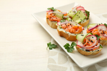Fototapeta premium Tasty canapes with salmon served on white wooden table, closeup. Space for text