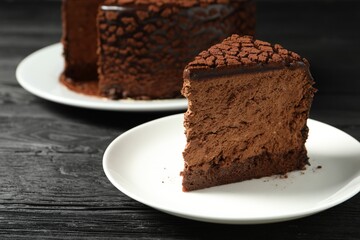 Piece of delicious chocolate truffle cake on black wooden table, closeup