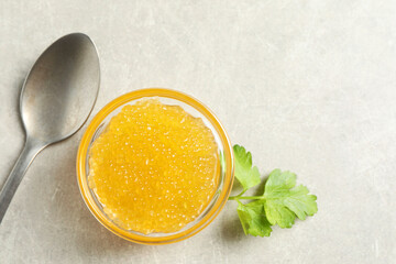 Fresh pike caviar in bowl, parsley and spoon on light grey table, top view. Space for text
