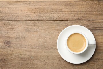 Aromatic coffee in cup on wooden table, top view. Space for text