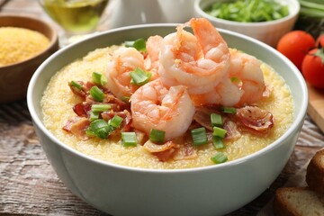 Fresh tasty shrimps, bacon, grits and green onion in bowl on wooden table, closeup