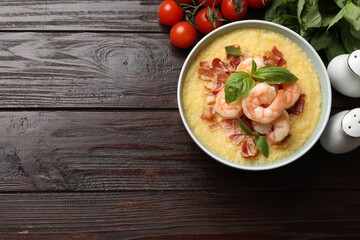 Fresh tasty shrimps, bacon, grits and basil in bowl on wooden table, flat lay. Space for text