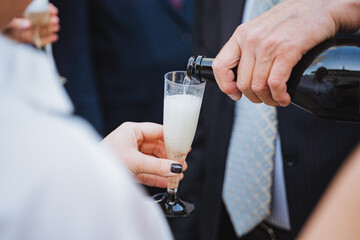 Man in formal wear pours champagne as woman holds glass at event