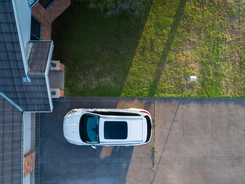 car with sunroof parked in duplex house driveway