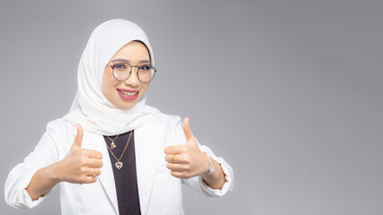 Portrait of Muslim woman in office attire and wearing a hijab. Corporate  or business people concept. Isolated on grey background. 16:9 ratio with copyspace on one side of the banner