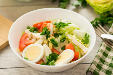 fresh vegetable salad, cabbage, tomatoes in a bowl on a wooden table