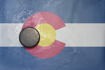 old hockey puck is on the ice with national flag of colorado state.