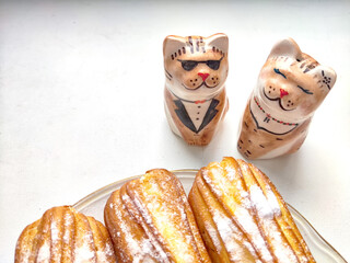 Delectable Dessert Pastries With Charming Porcelain Cat Figurines. Piped cakes sprinkled with sugar...