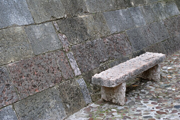 Close Up of Old Stone bench Beside Sloping Stone Castle Wall on Cobbles Street
