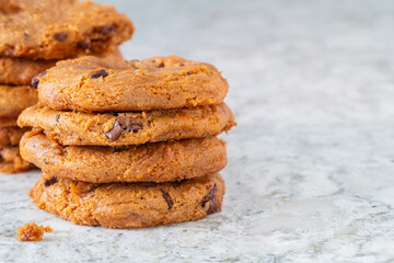 Stacks of hot and gooey chocolate chip cookies on a white granite counter