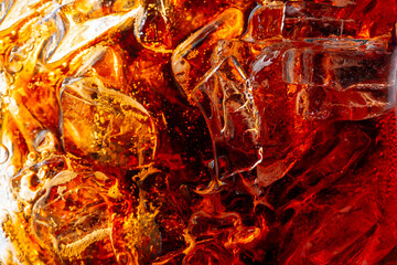 Cola drink surface close-up, top view,Close up view of the ice cubes in dark cola background. Texture of cooling sweet summer's drink with foam and macro bubbles on the glass wall.