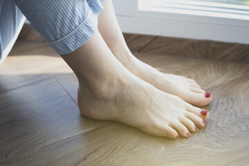 Woman sitting barefoot on the floor. Concept of underfloor heating and smart heating in the house.