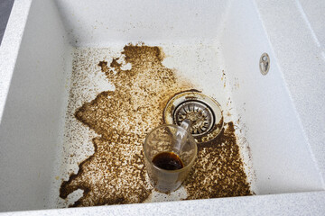 Woman is washing a dirty cup. Clogged drain water in wash basin sink. Dirty sink by coffee. Close...