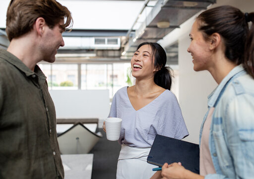 Three happy office workers talking together in an industrial co-working space