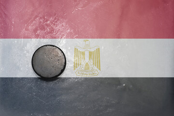 old hockey puck is on the ice with national flag of egypt .