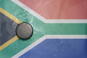 old hockey puck is on the ice with national flag of south africa .