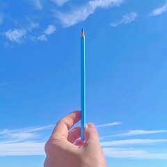 hand holds a sky blue pencil in the sky 