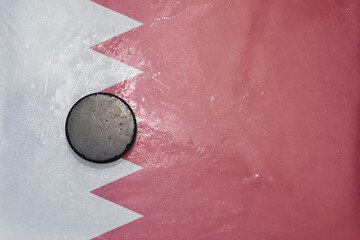 old hockey puck is on the ice with national flag of bahrain .