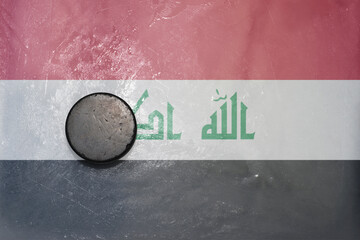 old hockey puck is on the ice with national flag of iraq .