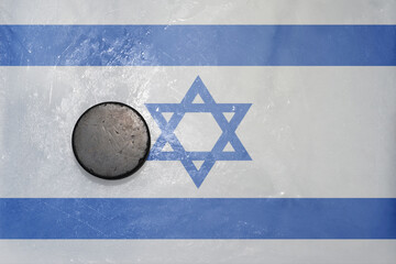 old hockey puck is on the ice with national flag of israel .