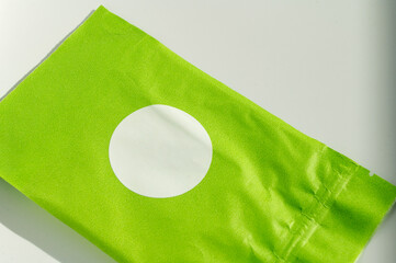 Round white sticker on green poly mailer envelope.