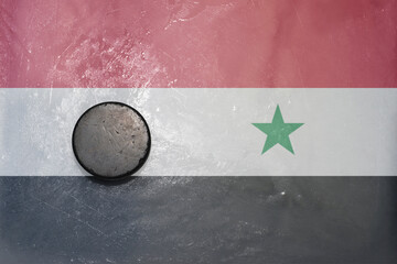 old hockey puck is on the ice with national flag of syria .