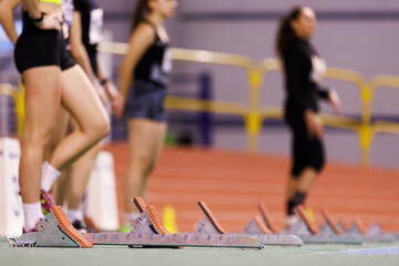 Young sportswomen preparing to start sprint on indoor track and field contest