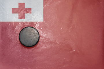 old hockey puck is on the ice with national flag of Tonga .