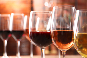 Different tasty wines in glasses against blurred background