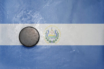 old hockey puck is on the ice with national flag of el salvador .