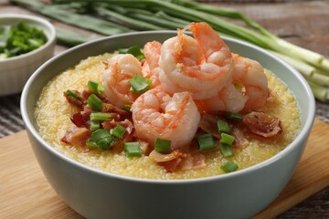Fresh tasty shrimps, bacon, grits and green onion in bowl on table, closeup