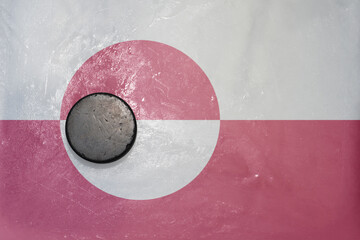 old hockey puck is on the ice with national flag of greenland .