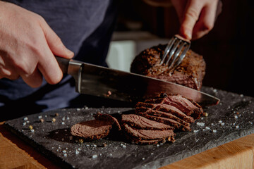 Steak cut into thin pieces and slices on a dark background